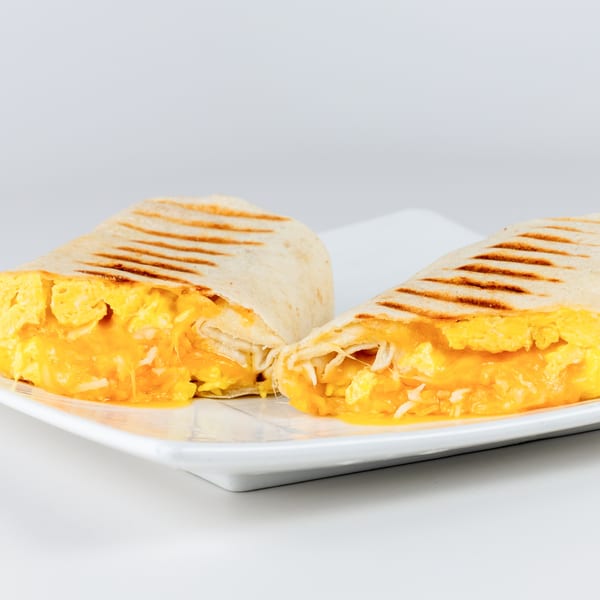 Two halves of a grilled breakfast burrito filled with scrambled eggs and melted cheese.