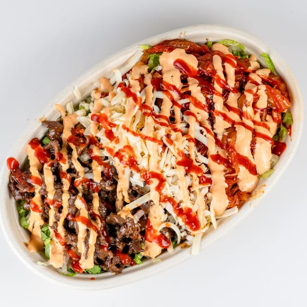 A Kudo Society Cafe bowl with beef, kimchi, shredded cheese, and two sauces.