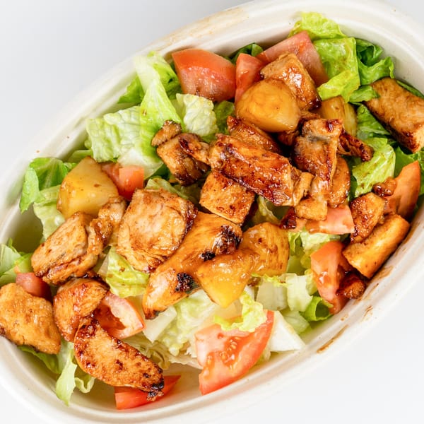 A Kudo Society Cafe salad with grilled chicken, lettuce, tomatoes, and pineapple in a bowl.